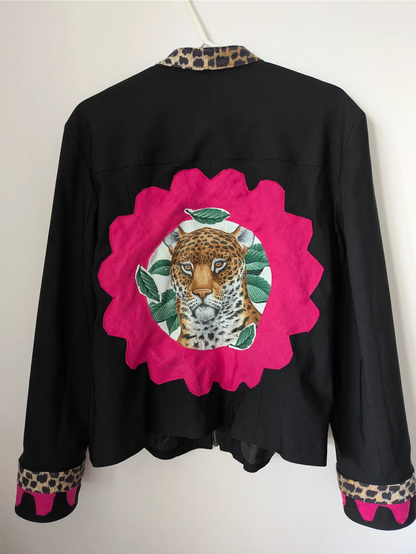 Black jacket with a pink floral patch featuring a leopard design on a white background