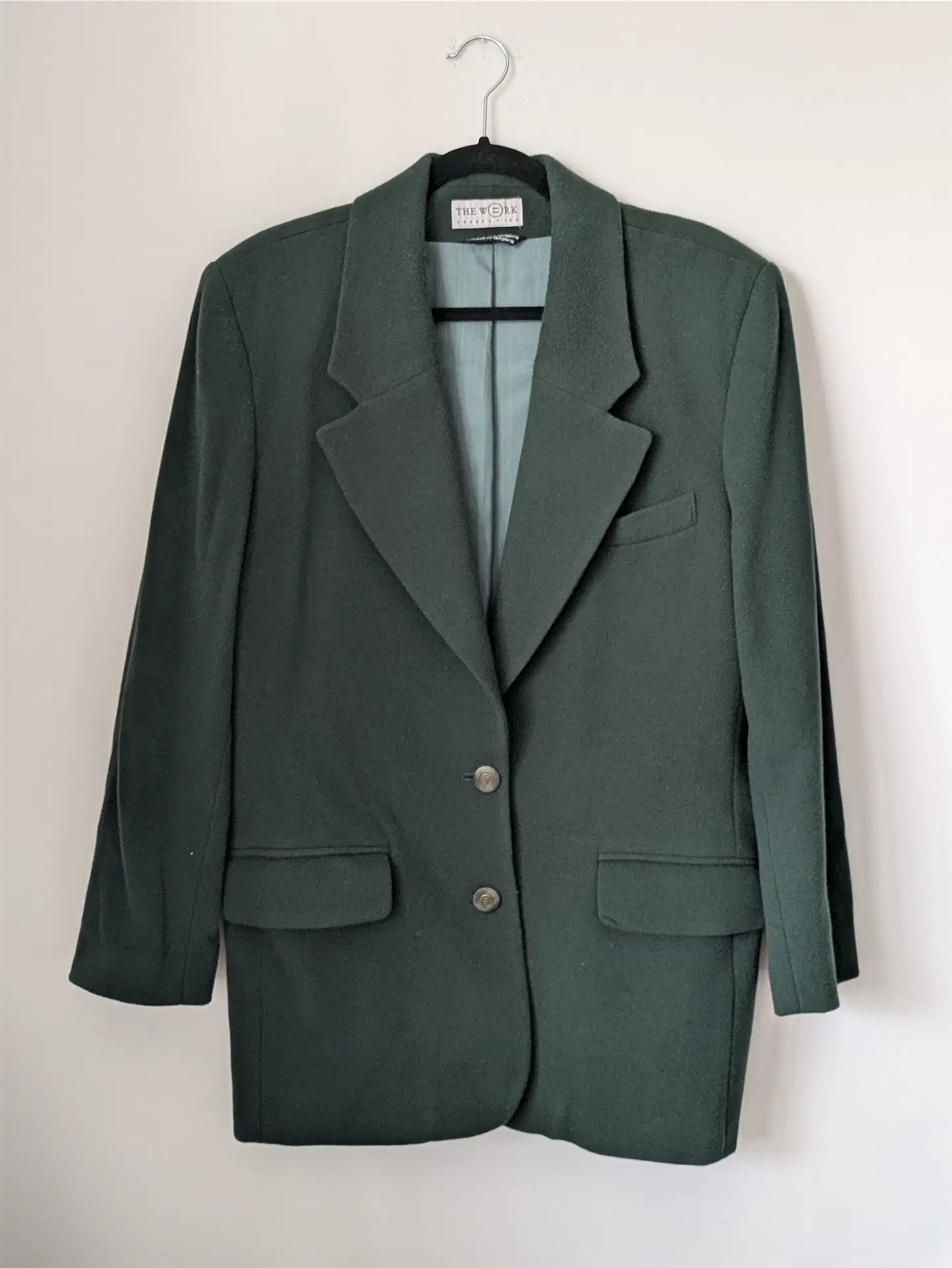 Green blazer on a hanger against a white background