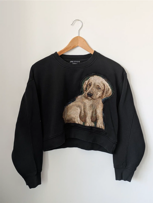 Black sweatshirt with a dog graphic on a hanger against a white background