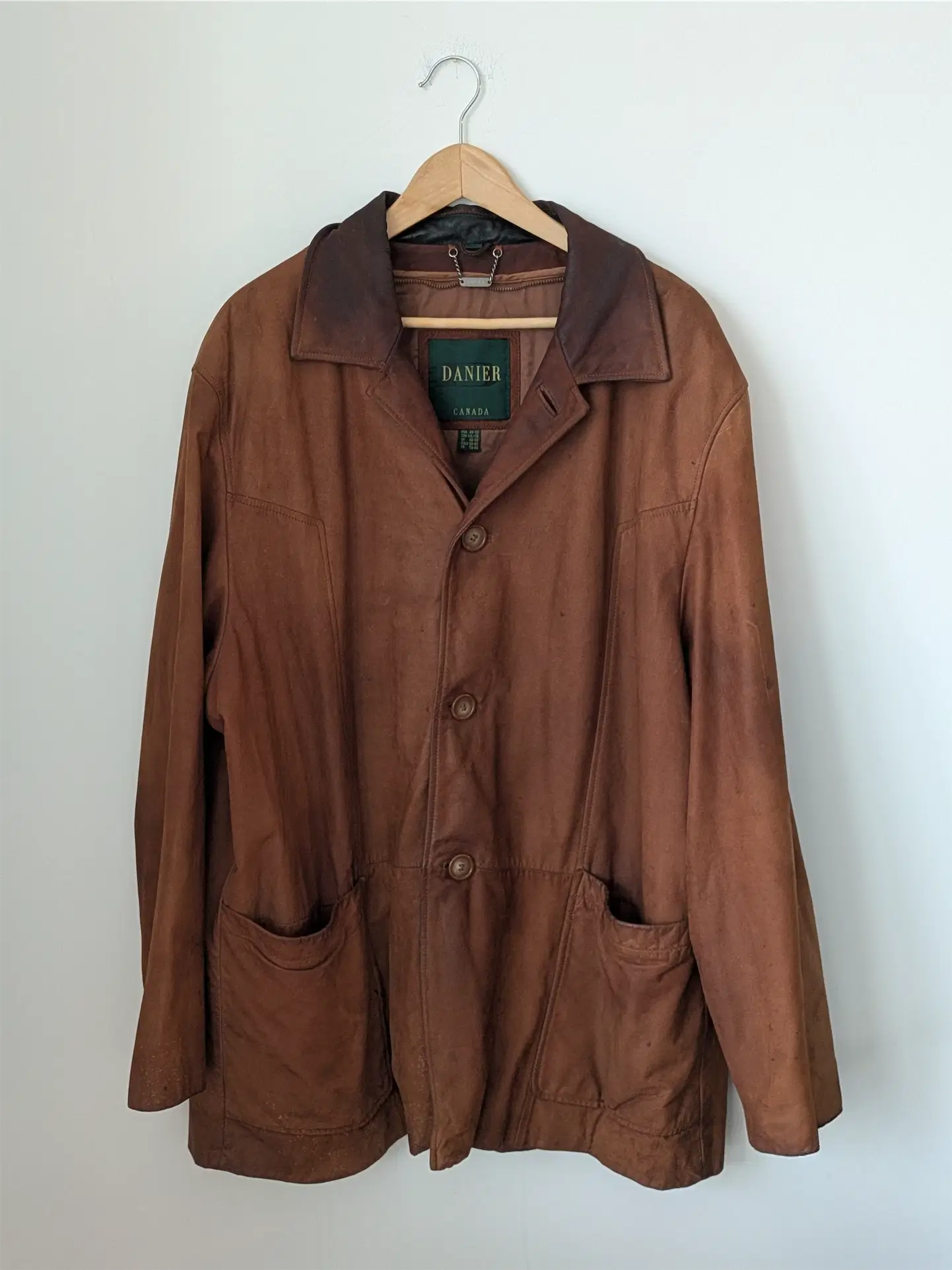 Brown jacket on a hanger against a white wall