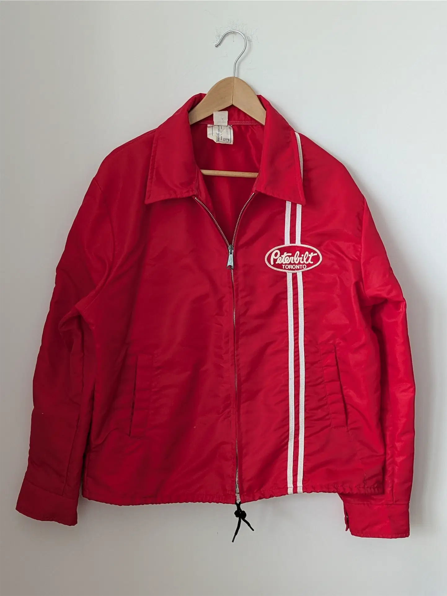 Red jacket with a logo on a hanger against a white background
